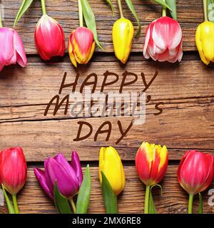 Flache Laienzusammensetzung mit schönen Tulpen und Satz HAPPY MOTHER's DAY auf Holzhintergrund Stockfoto