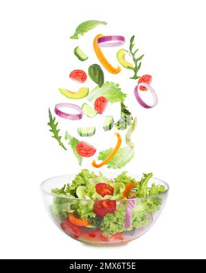 Frische Zutaten für leckeren Salat, der auf weißem Hintergrund in die Schüssel fällt Stockfoto