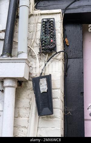 Defekte Telefonanschlussdose, die an einer Wand aufgehängt wurde und viele Kabel lose waren Stockfoto