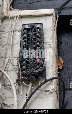 Defekte Telefonanschlussdose, die an einer Wand aufgehängt wurde und viele Kabel lose waren Stockfoto
