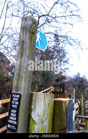 Schild für öffentlichen Fußweg mit Hundewarnung auf Holzpfahl in Cheshire Countryside UK Stockfoto