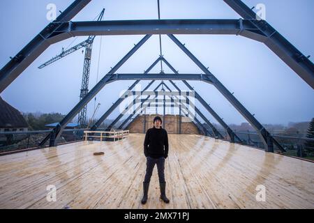 Teplitz, Deutschland. 26. Januar 2023. Der Gründer von Nordwolle, Marco Scheel, steht auf der Zwischendecke aus Holz in der Scheune aus Feldstein, die derzeit umgebaut wird. In den kommenden Monaten werden hier die Workshops zur Herstellung nachhaltiger Funktionsbekleidung aus Wolle von Pommerischen Schafen eingerichtet. Im Jahr 2018 zog Scheel sein Unternehmen, das er zwei Jahre zuvor auf der Insel Rügen gegründet hatte, nach Teplice und war in den Medien für seinen Kampf gegen die Behörden um notwendige Baugenehmigungen bekannt geworden. Kredit: Jens Büttner/dpa/Alamy Live News Stockfoto