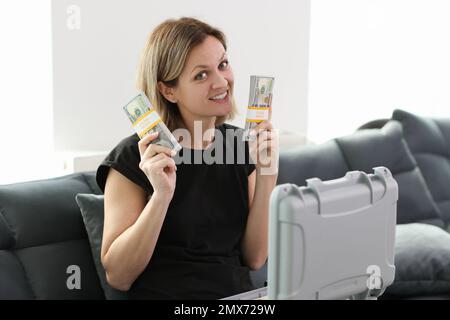 Eine Frau, die auf der Couch sitzt, zeigt eine Menge Geld Stockfoto