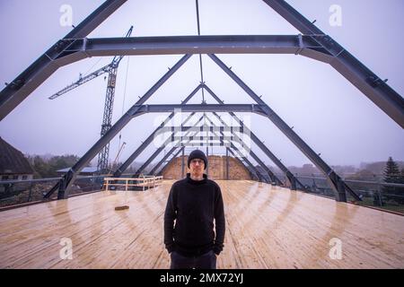 Teplitz, Deutschland. 26. Januar 2023. Der Gründer von Nordwolle, Marco Scheel, steht auf der Zwischendecke aus Holz in der Scheune aus Feldstein, die derzeit umgebaut wird. In den kommenden Monaten werden hier die Workshops zur Herstellung nachhaltiger Funktionsbekleidung aus Wolle von Pommerischen Schafen eingerichtet. Im Jahr 2018 zog Scheel sein Unternehmen, das er zwei Jahre zuvor auf der Insel Rügen gegründet hatte, nach Teplice und war in den Medien für seinen Kampf gegen die Behörden um notwendige Baugenehmigungen bekannt geworden. Kredit: Jens Büttner/dpa/Alamy Live News Stockfoto