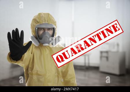 Mann in chemischem Schutzanzug mit STOPPGESTEN in Innenräumen. Prävention der Virusausbreitung Stockfoto