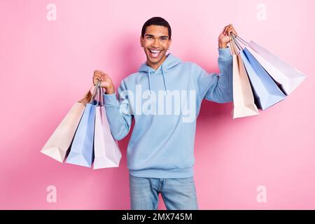 Fotosüchtig lustig, junger, überfreulicher Student, Shopaholic billige Kleidung Markenverkauf Halten viele Taschen aus zara isoliert auf rosa Hintergrund Stockfoto