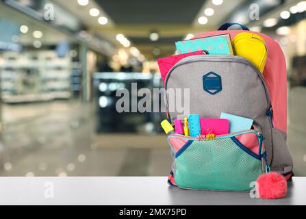 Heller Rucksack mit Schulpapier auf dem Tisch im Einkaufszentrum. Platz für Text Stockfoto