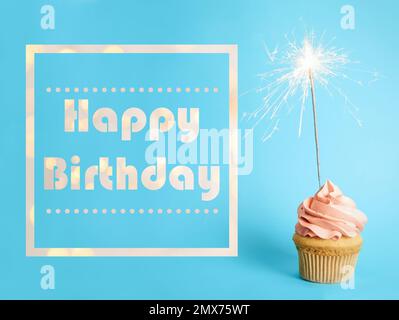 Text Happy Birthday and Delicious Cupcake with Sparkler on hell blue background (alles gute zum Geburtstag und leckerer Cupcake mit Funkeln auf hellblauem Hintergrund Stockfoto