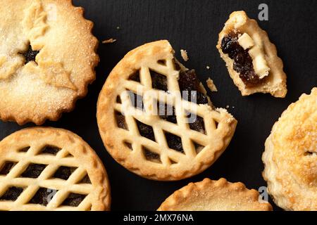 Alle Butterpasteten auf schwarzer Oberfläche. Eine zerbrochen, Fruchtfüllung sichtbar. Draufsicht. Stockfoto