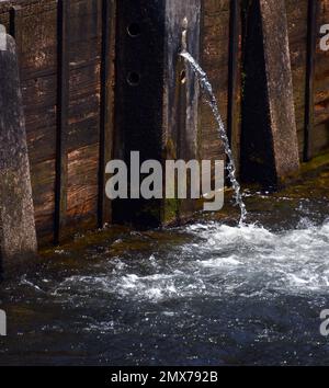 Der Weir-Staudamm aus Holz und Beton hält den South Holston River zurück. Durch das kleine runde Loch entweicht ein kleiner Strom. Stockfoto