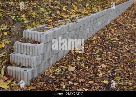 Eine Haltewand aus Betonelementen schützt den Fahrweg und den Bürgersteig vor Abrutschen. Stockfoto