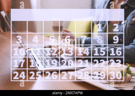 Kalender und Frau, die mit einem Laptop im Café arbeitet, schließen Stockfoto