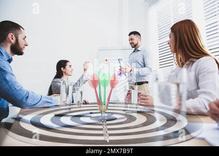 Leute, die Geschäftstreffen und ein Dartbrett mit Pfeilen haben. Doppelte Belichtung Stockfoto