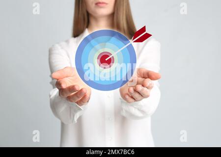 Junge Frau und Dartscheibe auf hellem Hintergrund, Nahaufnahme Stockfoto