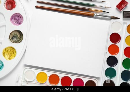 Aquarelle Farben, Pinsel und leeres Papier mit Platz für Design auf weißem Hintergrund, flach liegend Stockfoto