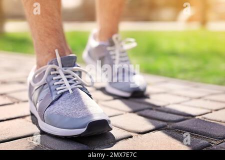 Sportlicher junger Mann in Trainingsschuhen im Freien an sonnigen Tagen, Nahaufnahme Stockfoto