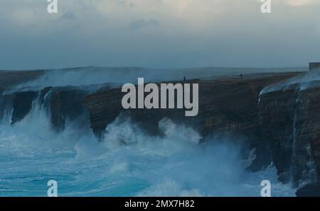 Menschen, die im Wintersturm auf den Yesnaby-Klippen spazieren, Orkney-Inseln Stockfoto