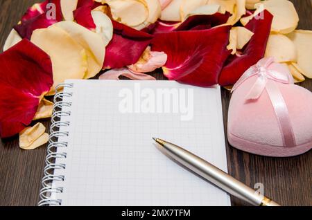 Blütenförmige Rose mit Geschenkbox und leerer Karte auf dem Tisch. valentinstag-Konzeptgeschichte Stockfoto