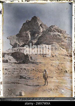 (Französisch - Quweira , Arabie ( actuelle Jordanie ) UN homme pose sous une falaise). Stockfoto