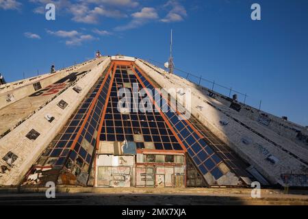 Erwachsene und Kinder klettern auf die Seite des Pyramidengebäudes, in dem sich das ehemalige Enver Hoxha Museum, Tirana, Albanien, befand. Stockfoto