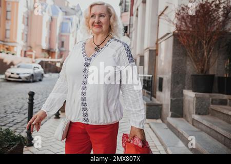 Schöne reife Frau auf einem Spaziergang in der Stadt. Außenporträt einer eleganten Frau mittleren Alters von 55 bis 60 Jahren, draußen Stockfoto