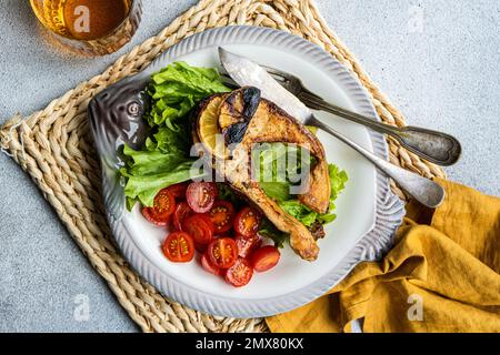 Gegrilltes Lachssteak mit Gemüse, serviert auf Fischteller und serviert mit einem Glas Weißwein Stockfoto