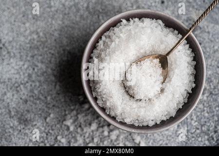 Kochkonzept von oben mit Meersalz in Keramikschüssel auf Betontisch Stockfoto