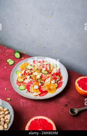 Top View von gesundem Salat mit Orangen und Erdbeeren und Äpfeln und Gurken serviert mit Käse und Pistazien auf dem Teller Stockfoto