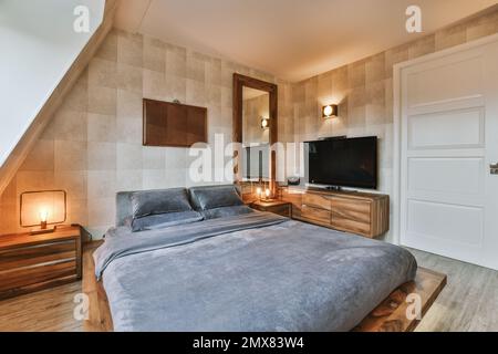 Innendesign des modernen Schlafzimmers mit komfortablem Bett zwischen Holzregalen und Lampen in der Nähe des Fernsehers am Schrank Stockfoto