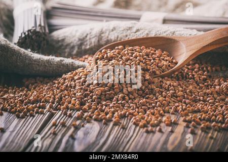 Stillleben im ländlichen Raum: Geschälter Grobgrieß von Buchweizen (Fagopyrum esculentum) und getrocknete Soba-Nudeln aus Buchweizenmehl auf Leinenbasis, Stockfoto