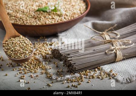 Ländliche Stillleben - traditionelle japanische Soba-Nudeln aus Buchweizenmehl und die geschälten Grütze aus Buchweizen, auf dem Hintergrund von Sackleinen, Nahaufnahme Stockfoto