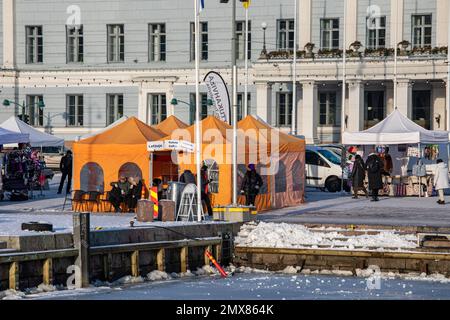 Orangefarbenes Café-Zelt am Helsinki Market Square an einem sonnigen Winternachmittag. Helsinki, Finnland. Stockfoto