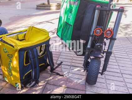 Caceres, Spanien - 19. Januar 2021: Lieferrucksäcke und elektrische Kicker. Urbaner Hintergrund Stockfoto