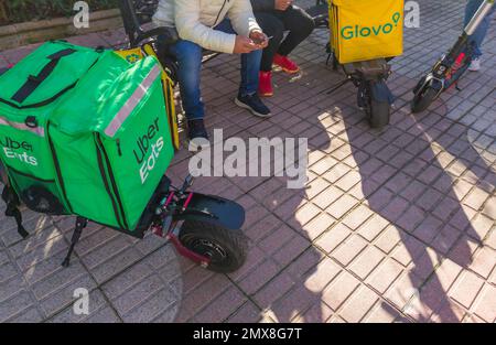 Caceres, Spanien - 19. Januar 2021: Lieferrucksäcke und elektrische Kicker. Urbaner Hintergrund Stockfoto