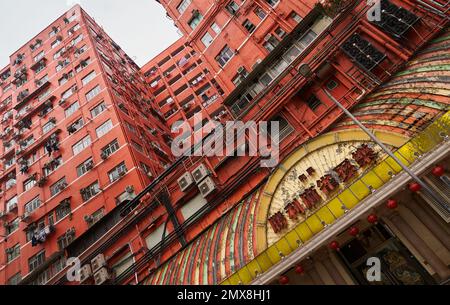 Niedriger Winkel Blick auf ein altes Apartmenthaus, das über die Straße in Hong Kong ragt. Stockfoto