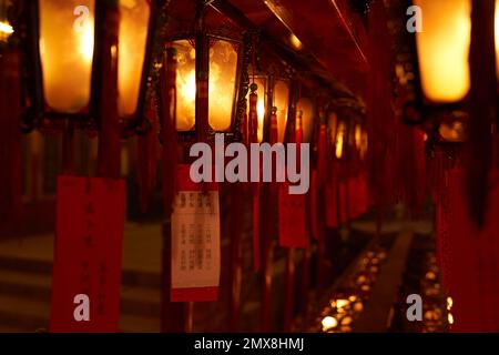 Rote Laternen mit Gebetsschildern und Quasten in einem buddhistischen Tempel in Hongkong. Stockfoto