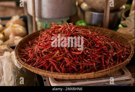 Ein Haufen roter Chilis in einem Bambuskorb auf einer Skala von einem lokalen Markt für Erzeugnisse in Myanmar (Birma). Stockfoto