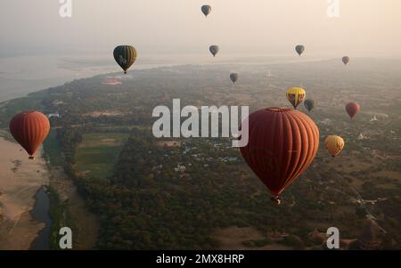Ein Luftblick auf eine Gruppe von Heißluftballons, die bei Sonnenaufgang über Bagan, Myanmar (Birma) fliegen. Stockfoto