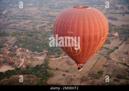 Luftaufnahme eines einzelnen Heißluftballons, der über eine Gruppe von Shan-Tempeln bei Sonnenaufgang in Bagan, Myanmar (Birma) fliegt. Stockfoto