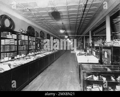 1930er Jahre Vintage Foto von Sears Roebuck und Co. Store Interior: Seltenes Original-Schwarz-weiß-Bild der historischen Einzelhandelsanzeige mit Art déco-Decke, Allstate-Reifen und Auto-Zubehör-Gängen – das amerikanische Einkaufserlebnis des frühen 20. Jahrhunderts einfängt Stockfoto