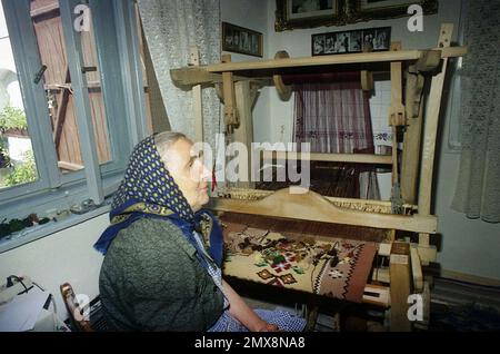 Poiana Sibiului, Kreis Sibiu, Rumänien, 2000. Eine einheimische Frau, die einen traditionellen Teppich mit einem Webstuhl in ihrem Haus webt. Stockfoto