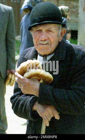 Sibiu County, Rumänien, ca. 1999. Älterer Mann, der aus der örtlichen Kirche kommt, in traditioneller schwarz-weißer Kleidung und Kopfbedeckungen. Stockfoto