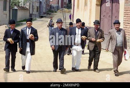 Sibiu County, Rumänien, ca. 1999. Eine Gruppe von Männern, die nach dem Sonntagsgottesdienst in der Kirche auf einer Dorfstraße spazieren gehen. Stockfoto