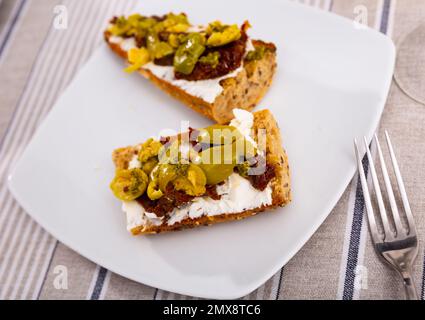 Getoastete Sandwiches mit Frischkäse, sonnengetrockneten Tomaten und Oliven Stockfoto