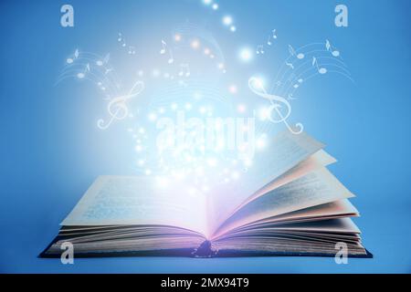 Symphonie mit musikalischen Noten aus einem offenen Buch auf blauem Hintergrund Stockfoto
