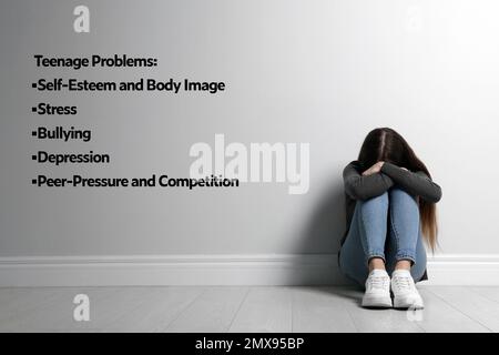 Trauriges Mädchen, das auf dem Boden sitzt und unter Teenager-Problemen leidet Stockfoto