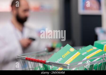 Selektiver Fokus auf Korb voll mit Supplementpaketen, die an der Theke in der Apotheke stehen. Im Hintergrund Apotheker-Scanning-Produkte, verantwortlich für die Verwaltung des Bestands an Pillen Stockfoto