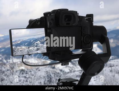 Wunderschöne Aussicht auf schneebedeckte Berge mit professioneller Videokamera Stockfoto