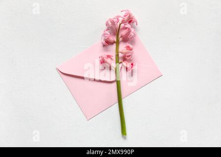 Umschlag und wunderschöne Hyazinthen-Blume auf hellem Hintergrund Stockfoto