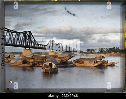 Hà-Nôi, Tonkin, Indochina sampans beim Sonnenuntergang auf dem Roten Fluss vor der Doumer Brücke, Léon ist in Indochina sehr beschäftigt Stockfoto